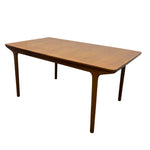 Load image into Gallery viewer, A mid-century modern wooden dining table with a warm medium-brown finish, featuring angled legs and a tapered rectangular top, shown against a plain white background.
