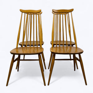 Two wooden chairs with spindle backs on a white background