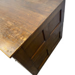 Load image into Gallery viewer, A close-up of a rustic wooden furniture piece, showing the top surface with visible wear and tear, and a side panel with recessed paneling, isolated on a white background.
