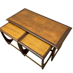 Load image into Gallery viewer, Three nested wooden nesting tables with a warm medium-brown wood grain finish and dark brown edges, shown on a plain white background.
