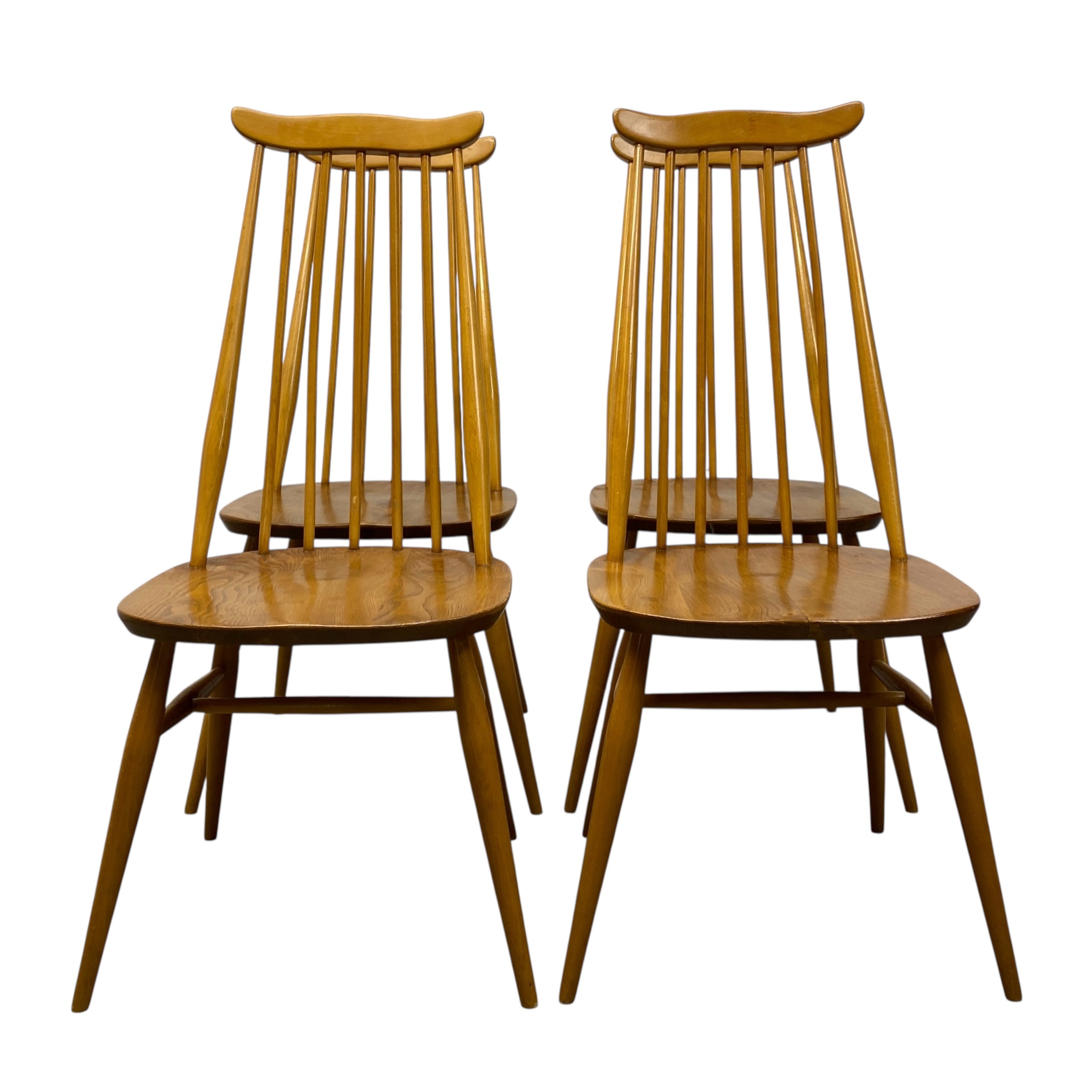 Four wooden chairs with spindle back design on a white background
