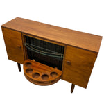 Load image into Gallery viewer, Mid-century modern wooden sideboard cabinet with a warm walnut finish, featuring two doors, a glass-front center cabinet, and a pull-out circular wooden tray with six cup holders, shown on a white background.
