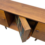 Load image into Gallery viewer, Mid-century modern wooden credenza or sideboard with a warm walnut finish, featuring two cabinet doors with small square pulls and an open center door revealing a built-in bookshelf with books.
