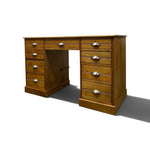 Load image into Gallery viewer, A mid-century wooden writing desk with a warm medium-brown finish, featuring multiple drawers on both sides and a central open space, finished with brass-colored metal drawer pulls, shown on a white background with a soft shadow.
