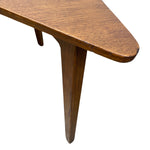 Load image into Gallery viewer, Close-up of a mid-century modern wooden table corner with a triangular top and tapered legs, showing the warm brown wood grain against a white background.
