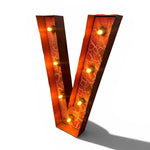 Load image into Gallery viewer, A large decorative letter V marquee light with a warm orange and red crackled glass face, illuminated by multiple warm yellow bulbs, shown on a white background with a soft shadow.
