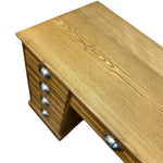 Load image into Gallery viewer, A close-up of a light natural wood desk with multiple drawers and silver metal drawer pulls, shown on a plain white background.
