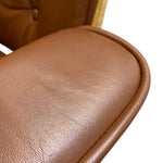 Load image into Gallery viewer, Close-up of a brown leather upholstered chair armrest with visible grain texture and a stitched edge, against a white background.
