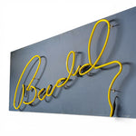 Load image into Gallery viewer, Neon sign with yellow cursive text on a BLUE background
