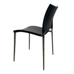Load image into Gallery viewer, A modern black dining chair with a curved seat and backrest, supported by slim metallic legs, shown from a three-quarters angle on a plain white background.
