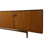 Load image into Gallery viewer, Mid-century modern wooden credenza with two doors, a warm medium-brown wood grain finish, and small square metal handles, shown against a plain white background.
