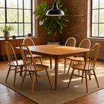 Load image into Gallery viewer, A mid-century modern wooden dining table set with six matching spindle-back chairs in a warm, sunlit loft dining room with brick walls and large windows.

