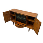 Load image into Gallery viewer, A mid-century modern wooden bar cabinet with open doors and a folded-down lower section showing a wine rack and cup holders, photographed on a white background.
