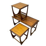 Load image into Gallery viewer, Three wooden nesting tables with a warm medium-brown finish and distinctive curved metal support frames, shown on a plain white background.
