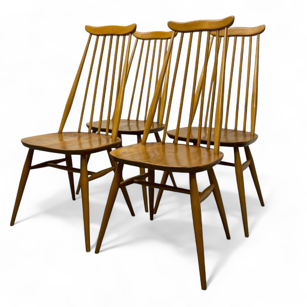 Four wooden chairs with spindle backs on a white background