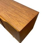 Load image into Gallery viewer, Close-up of a mid-century modern wooden cabinet corner showing the warm brown wood grain finish against a white background.
