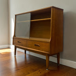 Load image into Gallery viewer, Mid-century modern wooden hutch cabinet with two glass-front doors, one open shelf, and two drawers with metal pulls, shown on a hardwood floor against a neutral wall.
