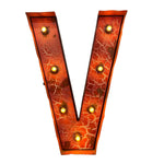 Load image into Gallery viewer, A large decorative letter V marquee light with a distressed orange and red cracked enamel-style face, outlined in dark metal, and illuminated by multiple warm yellow bulbs set along the inner edge, shown on a plain white background.
