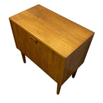 Load image into Gallery viewer, A mid-century modern wooden sideboard or cabinet with a warm honey-toned wood grain finish, featuring a single drawer with a horizontal pull handle and tapered legs, shown on a plain white background.
