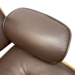 Load image into Gallery viewer, Close-up of a brown leather lounge chair showing the padded headrest and part of the seat, with a thin light wood edge visible against a white background.
