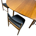 Load image into Gallery viewer, A mid-century modern dining table and chairs set, featuring a warm walnut wood oval table with extendable leaves and black leather upholstered chairs with wooden frames, shown on a white background.
