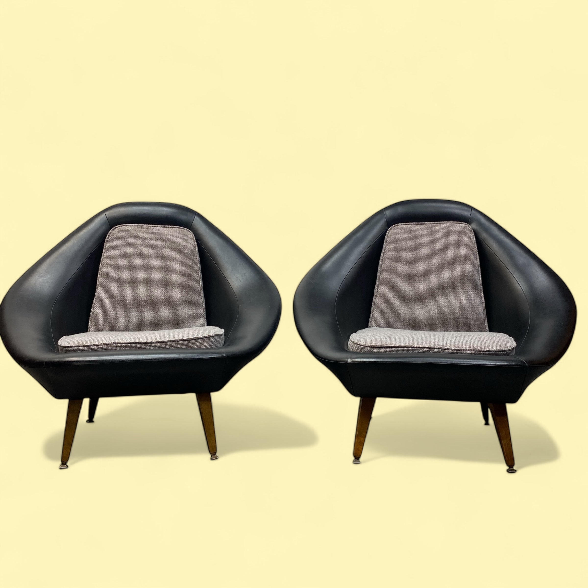 Two black armchairs with gray cushions on a beige background