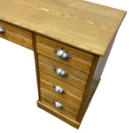 Load image into Gallery viewer, A light oak wood writing desk with a five-drawer pedestal on the right and a drawer section on the left, featuring silver metal drawer pulls, shown on a white background.
