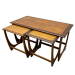 Load image into Gallery viewer, A set of three nested wooden nesting tables with a warm medium-brown finish and lighter honey-wood top surfaces, shown on a plain white background.
