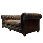 Load image into Gallery viewer, A vintage-style Chesterfield loveseat sofa upholstered in distressed dark brown leather, featuring deep button tufting, rolled arms, and dark wooden feet, shown against a plain white background.
