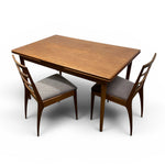 Load image into Gallery viewer, A mid-century modern wooden dining table with two matching wooden chairs featuring gray upholstered seats, shown on a plain white background.
