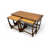 Load image into Gallery viewer, A set of three nested wooden nesting tables with a warm medium-brown finish and lighter natural wood inlay on the tabletops, shown on a clean white background.
