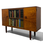Load image into Gallery viewer, Mid-century modern wooden sideboard cabinet with two doors, two open bookshelves filled with books, and tapered legs, photographed on a white studio background.

