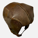 Load image into Gallery viewer, A vintage brown leather protective helmet with stitched paneling and a chin strap, shown against a plain light gray background.
