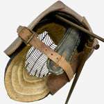 Load image into Gallery viewer, A vintage leather helmet with a wire face mask, tan leather straps, and a dark gray padded interior, shown on a plain light gray background.
