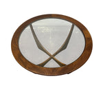 Load image into Gallery viewer, An oval wooden table with a thick medium-brown wood frame and a clear glass top, showing a reflection of the room beneath.
