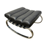 Load image into Gallery viewer, A modern black leather ottoman with a curved polished chrome metal base, photographed on a solid white background.
