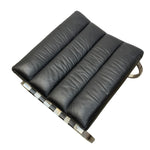 Load image into Gallery viewer, A modern black leather ottoman or seat cushion with vertical channel tufting and a polished metal frame, shown on a plain white background.
