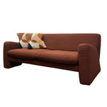 Load image into Gallery viewer, A mid-century modern upholstered loveseat sofa in a warm rust-brown fabric, featuring a patterned accent pillow, shown against a plain white background.
