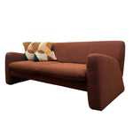 Load image into Gallery viewer, A mid-century modern upholstered loveseat sofa in a warm rust-brown fabric, featuring a textured geometric throw pillow with cream, orange, and dark accents, set against a plain white background.

