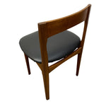 Load image into Gallery viewer, A mid-century modern wooden dining chair with a warm brown teak wood frame and a black upholstered seat cushion, shown from a three-quarters angle on a white background.
