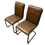 Load image into Gallery viewer, Two matching brown leather dining chairs with ribbed backs and seats on black metal cantilever legs, shown on a plain white background.
