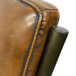 Load image into Gallery viewer, Close-up detail of a brown leather armrest with dark stitching and a dark metal cylindrical support against a white background.
