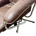 Load image into Gallery viewer, Close-up of a brown leather recliner chair showing the padded armrest, stitching, and polished metal support frame against a white background.
