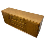 Load image into Gallery viewer, A mid-century modern wooden sideboard with a warm honey-brown finish, featuring three drawers on the left with round knobs, two lower drawers in the center, and a cabinet door on the right with a matching round pull.
