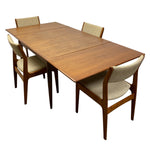 Load image into Gallery viewer, A mid-century modern wooden dining table set with four upholstered chairs, shown on a solid white background.
