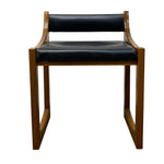 Load image into Gallery viewer, A mid-century modern wooden dining chair with a warm brown wood frame and black leather seat and backrest cushions, shown against a plain white background.
