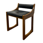 Load image into Gallery viewer, A mid-century modern wooden chair with a warm brown wood frame and black leather seat and backrest cushions, shown on a plain white background.
