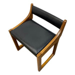 Load image into Gallery viewer, A mid-century modern wooden dining chair with a warm medium-brown wood frame and black upholstered seat and backrest, shown from an elevated angle on a white background.
