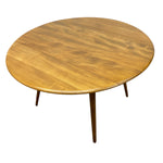 Load image into Gallery viewer, A round wooden dining table with a warm golden-brown finish and tapered legs, shown on a plain white background.
