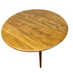 Load image into Gallery viewer, A round wooden dining table with a warm golden-brown finish and a single tapered leg, shown from a high angle on a white background.
